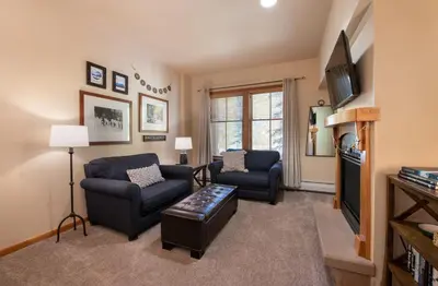 a living room with two chairs and a tv at Zephyr Mountain Lodge Premium-Rated 2108 in Winter Park
