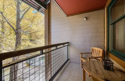 a balcony with a wooden table and a window at Zephyr Mountain Lodge Premium-Rated 2108 in Winter Park