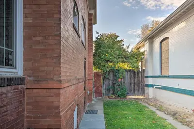 a brick building with a sidewalk next to a house at Steps to City Park and Restaurants Denver Studio in Denver