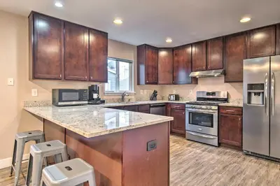 a kitchen with wooden cabinets and stainless steel appliances at Walk to Broncos Stadium Modern Denver Duplex in Denver