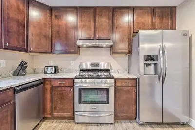 a kitchen with wooden cabinets and stainless steel appliances at Walk to Broncos Stadium Modern Denver Duplex in Denver