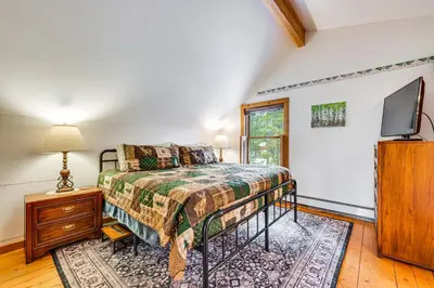 a bedroom with a bed and a flat screen tv at Deck, Fire Pit and Grill Log Cabin in Black Hawk in Black Hawk