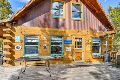 a wooden cabin with a bench in front of it at Deck, Fire Pit and Grill Log Cabin in Black Hawk in Black Hawk