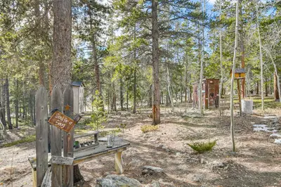 a wooden bench in the middle of a forest at Deck, Fire Pit and Grill Log Cabin in Black Hawk in Black Hawk