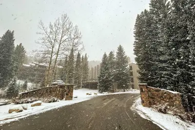 a snow covered road with trees on the side at Ski-InandSki-Out Winter Park Condo with Balcony! in Winter Park