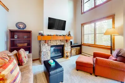 a living room with a fireplace and a tv at Knocking at Nature's Door in Keystone