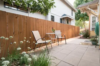 a fence with a table and chairs on a patio at Cozy Victorian Cottage in the Heart of Old Town! in Fort Collins