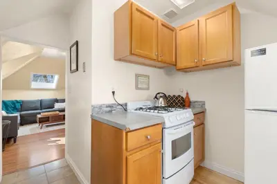 a kitchen with wooden cabinets and a stove top oven at Cozy Victorian Cottage in the Heart of Old Town! in Fort Collins