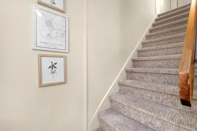 a stairway with two pictures on the wall and a stair case at Cozy Victorian Cottage in the Heart of Old Town! in Fort Collins