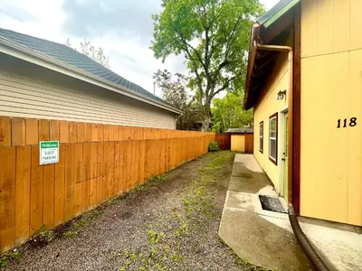 a fence is next to a house with a driveway at Cozy Victorian Cottage in the Heart of Old Town! in Fort Collins