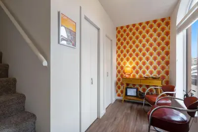 a hallway with an orange accent wall in a house at Pine Street Loft Steps from Old Town Square in Fort Collins