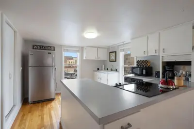 a kitchen with white cabinets and a stainless steel refrigerator at Pine Street Loft Steps from Old Town Square in Fort Collins