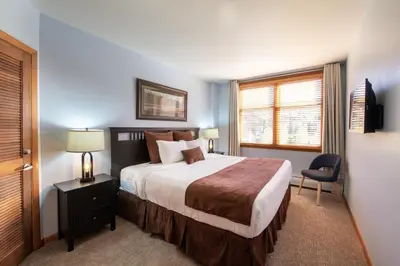 a bedroom with a bed and a chair and a window at Zephyr Mountain Lodge Premium-Rated 2416 in Winter Park