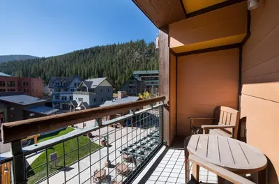 a balcony with a bench and a view of a town at Zephyr Mountain Lodge Premium-Rated 2416 in Winter Park