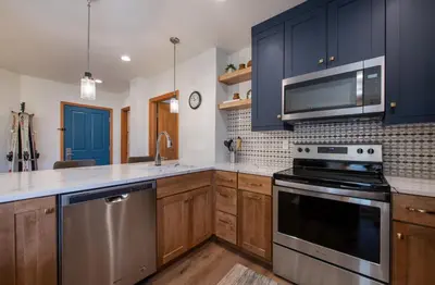 a kitchen with blue cabinets and stainless steel appliances at Zephyr Mountain Lodge Premium-Rated 2416 in Winter Park