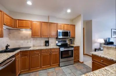 a kitchen with wooden cabinets and a stove top oven at Zephyr Mountain Lodge Value-Rated 2508 in Winter Park