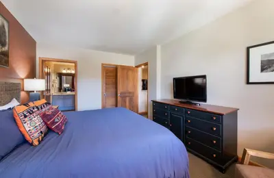 a bedroom with a blue bed and a flat screen tv at Zephyr Mountain Lodge Select-Rated 2510 in Winter Park