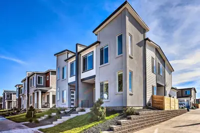 a white house with blue windows on a street at 6 Mi to Dtwn Denver Townhome with Patio! in Thornton