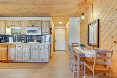 a kitchen with wooden cabinets and a table in a room at Near Skiing Studio with Pool Access in Granby! in Granby