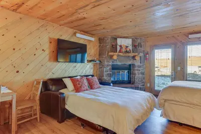 a bedroom with two beds and a stone fireplace at Near Skiing Studio with Pool Access in Granby! in Granby