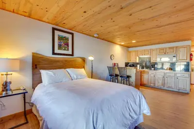 a bedroom with a large bed and a kitchen at Near Skiing Studio with Pool Access in Granby! in Granby