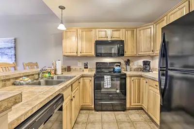 a kitchen with wooden cabinets and a black refrigerator at Spacious Fraser Condo about 6 Mi to Winter Park! in Fraser