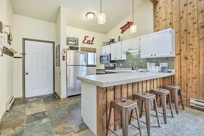 a kitchen with white cabinets and bar stools at Winter Park Condo with Hot Tub, 3 Mi to Slopes! in Winter Park