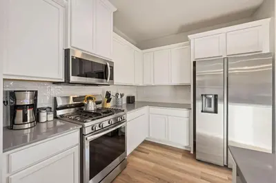 a kitchen with white cabinets and a stainless steel refrigerator at Hidden Gem - Brand New Curated Home with Pool Access in Fort Collins