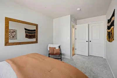 a bedroom with a bed with an orange blanket at Hidden Gem - Brand New Curated Home with Pool Access in Fort Collins