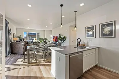 a kitchen and living room with a sink and a table at Hidden Gem - Brand New Curated Home with Pool Access in Fort Collins