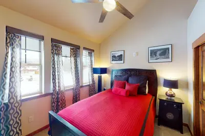 a bedroom with a red bed with two windows at Byers Peak Penthouse in Fraser