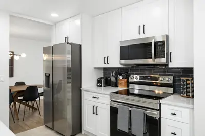 a kitchen with white cabinets and a stainless steel refrigerator at #Marbella Lane - Modern & Spacious 4BR Retreat in Arvada in Arvada
