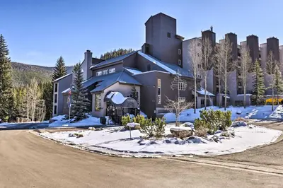 a large house in the snow with a road in front at Cozy Ski-InandSki-Out Winter Park Resort Condo! in Winter Park