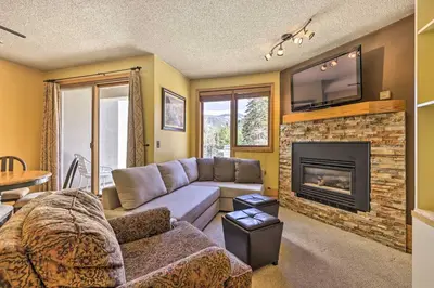 a living room with a couch and a fireplace at Cozy Ski-InandSki-Out Winter Park Resort Condo! in Winter Park