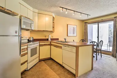 a kitchen with a refrigerator and a sink and a table at Cozy Ski-InandSki-Out Winter Park Resort Condo! in Winter Park