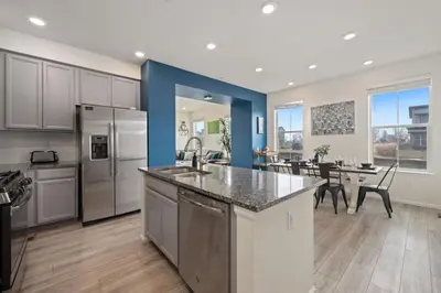 a kitchen with stainless steel appliances and a dining room at Modern & Stunning Home near Breweries and Old Town in Fort Collins