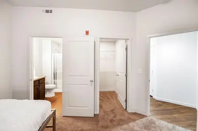 a white bedroom with a bed and a bathroom at Relaxing 3BR Apartment With Pool & Wifi in Greeley