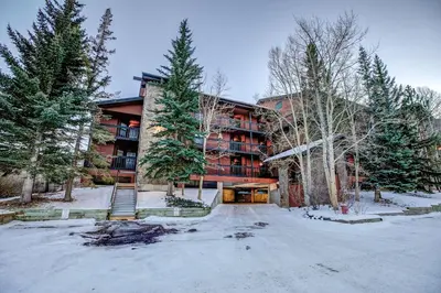 a building in the snow with trees in front of it at Mountainside Pineview Condo: Cozy Frisco Retreat in Frisco
