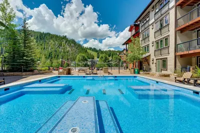 a large swimming pool in front of a building at Ski-InandSki-Out Winter Park Condo with Balcony in Winter Park