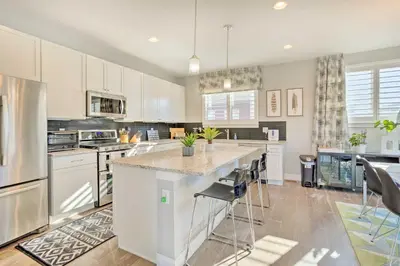 a kitchen with white cabinets and a island with bar stools at Private Balcony Pet-Friendly Denver Escape! in Denver