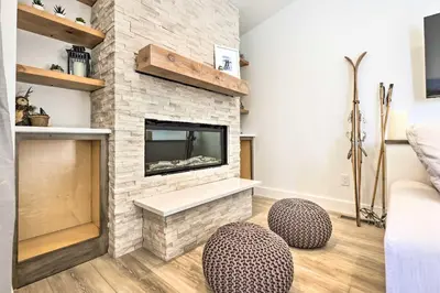 a living room with a stone fireplace with two stools at Chic Condo with Fireplace Walk to Main St Frisco! in Frisco
