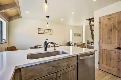 a kitchen with a stainless steel sink and wooden cabinets at Chic Condo with Fireplace Walk to Main St Frisco! in Frisco
