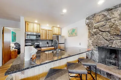 a kitchen with a fireplace and a stone wall at The Sanctuary Bldg 5 #7-8 in Winter Park