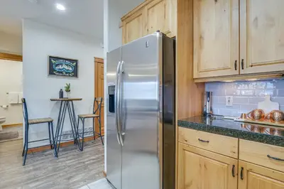a kitchen with a stainless steel refrigerator and wooden cabinets at Winter Park Condo with Balcony and Mtn Views! in Winter Park