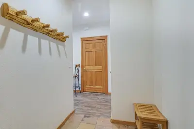 a hallway with a wooden door and a wooden stool at Winter Park Condo with Balcony and Mtn Views! in Winter Park