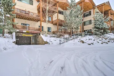 a snow covered street in front of a building at Winter Park Condo with Balcony and Mtn Views! in Winter Park