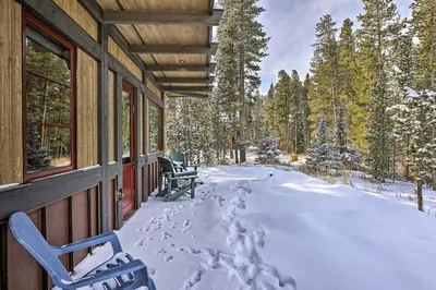 a house covered in snow with two chairs on the porch at Cozy Fraser Cabin with Views and Moose Sightings! in Fraser