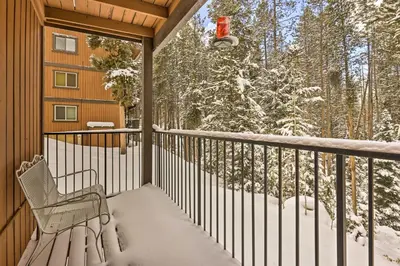 a porch with a bench and snow covered trees at Gorgeous Winter Park Condo with Private Deck! in Winter Park