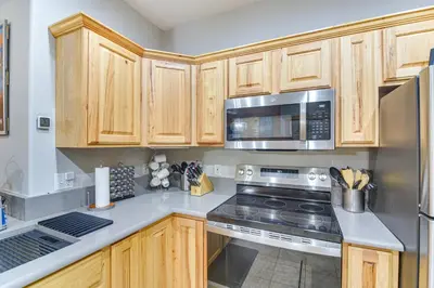 a kitchen with wooden cabinets and stainless steel appliances at Patio and Mountain Views Central Grand Lake Condo! in Grand Lake