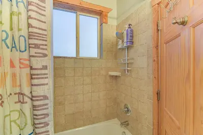 a bathroom with a tub and a shower with a window at Patio and Mountain Views Central Grand Lake Condo! in Grand Lake